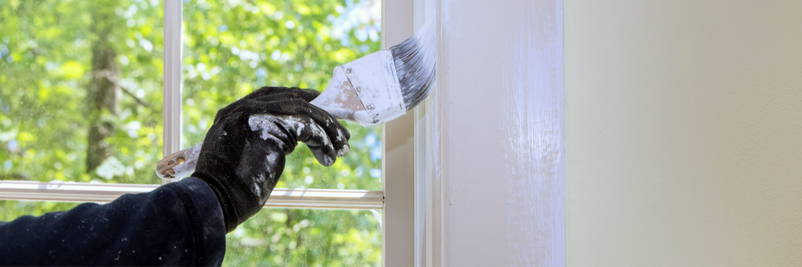 Maler sprüht weiße Farbe auf Fensterrahmen bei Renovierungsarbeiten, Malerbetrieb Maier-Quantius