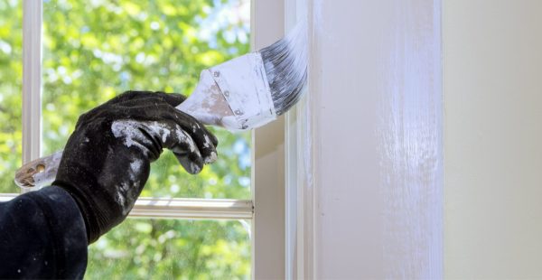Maler sprüht weiße Farbe auf Fensterrahmen bei Renovierungsarbeiten, Malerbetrieb Maier-Quantius