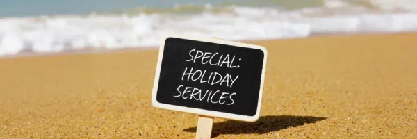Schild mit Holiday Services am Strand als Symbol für Urlaubsservice, Malerbetrieb Maier-Quantius